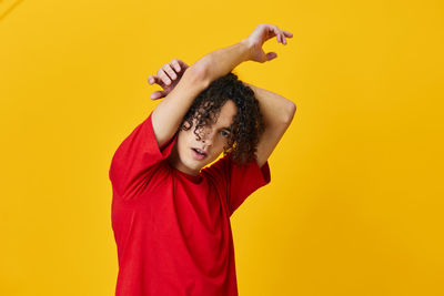 Portrait of young man gesturing against yellow background
