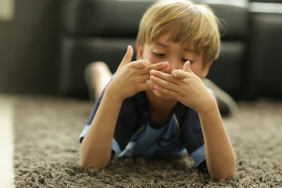 Close-up of boy lying on rug at home