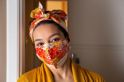 Portrait of woman wearing mask standing at home