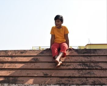 Low angle view of boy on staircase against sky