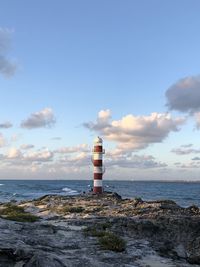 Lighthouse by sea against sky