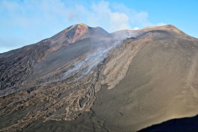 Low angle view of volcanic mountain against blue sky