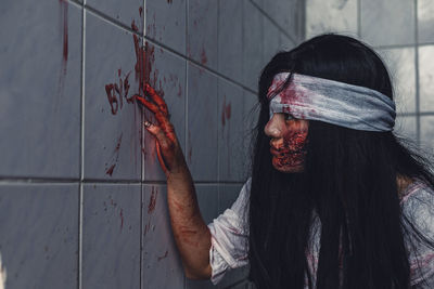 Woman writing bye with blood on wall