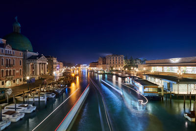 Illuminated buildings in city against clear sky at night