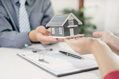 Midsection of real estate agent with model house in office