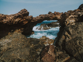 Rock formation on beach against sky