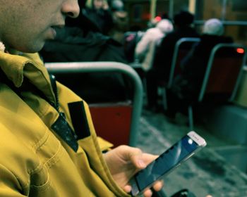 Close-up of man using mobile phone in bus