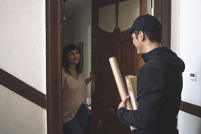 Smiling customer talking to delivery man at doorstep