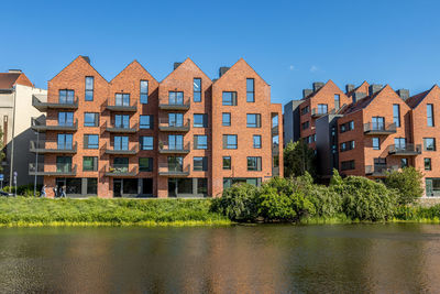 Residential buildings by river against sky