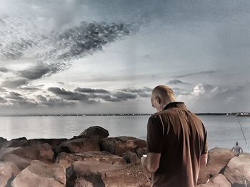 Rear view of man looking at sea against sky