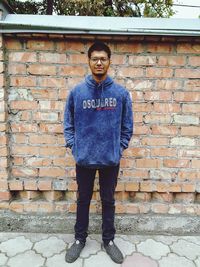 Portrait of man standing against brick wall