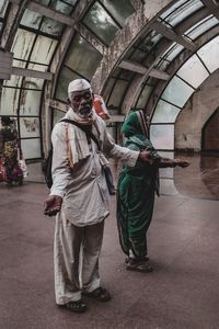 Full length of couple begging on train station