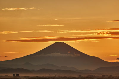 Scenic view of silhouette mountains against orange sky during sunset