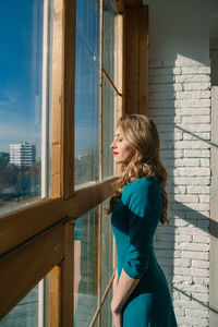 Side view of young woman looking through window