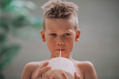 Close-up portrait of shirtless boy holding camera