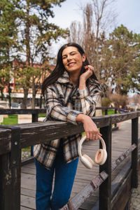 Portrait of smiling young woman sitting on bench at park