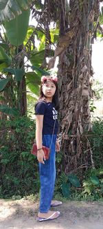 Full length portrait of girl standing against trees
