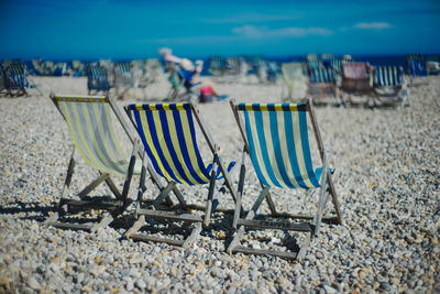 Chairs on sand at beach against sky