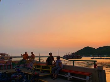 People sitting on boat in sea against sky during sunset