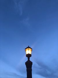 Low angle view of illuminated street light against blue sky