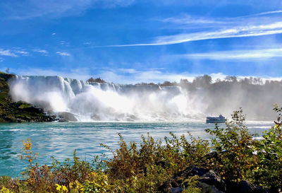 Scenic view of waterfall against cloudy sky