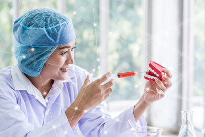 Smiling scientist injecting to dentures at lab