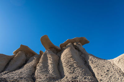 Bisti badlands landscape of dramatic grey hoodoos or caprock formations against blue sky 
