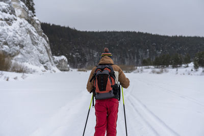 Rear view of man skiing on snow covered field