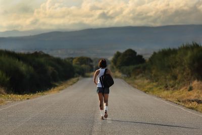 Rear view of woman walking on road against sky