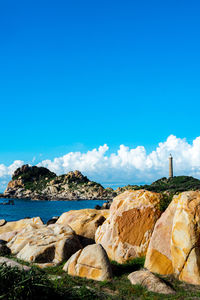 Rocks by sea against blue sky