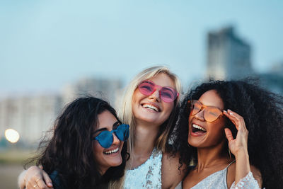 Portrait of smiling young woman wearing sunglasses against sky