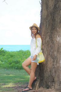 Smiling woman standing by tree trunk