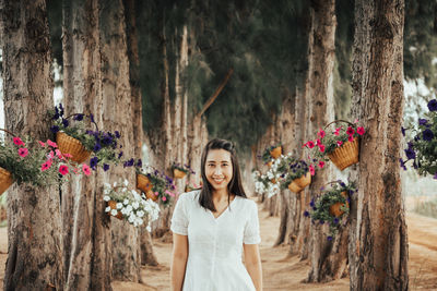 Portrait of smiling woman standing by trees