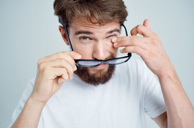 Close-up portrait of man holding eyeglasses