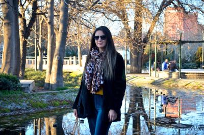 Portrait of young woman standing against river