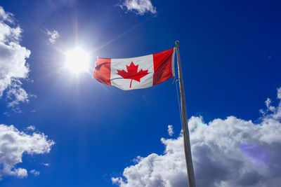 Low angle view of canadian flag against blue sky