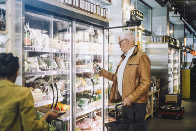 Senior man analyzing jar at grocery store