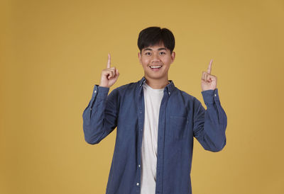 Portrait of smiling man standing against yellow background