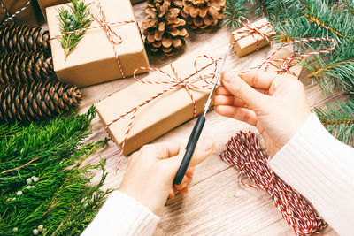 High angle view of woman packing gift by decoration on table