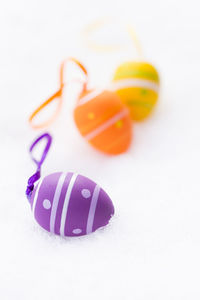 Closeup of purple, orange and yellow easter eggs with ribbons, stripes and dots on snow in spring