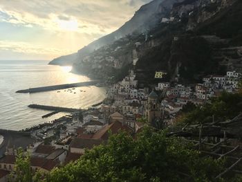 Town by sea against sky during sunset