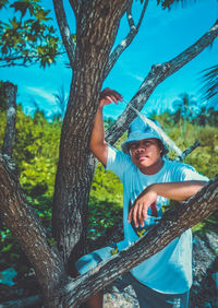 Portrait of young woman standing by tree