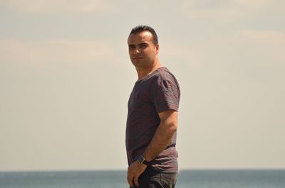 Portrait of man standing on beach against sky