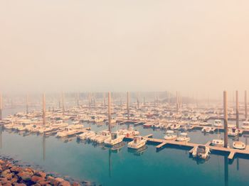 Boats moored at harbor against sky during sunset