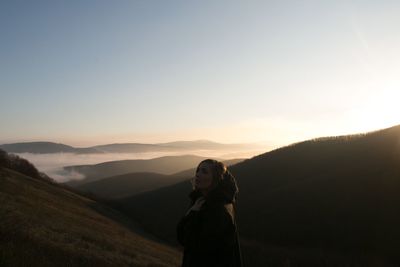 Woman standing on mountain against clear sky