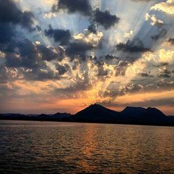 Scenic view of mountains against cloudy sky at sunset