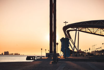 Silhouette man standing on pier by sea against sky during sunset