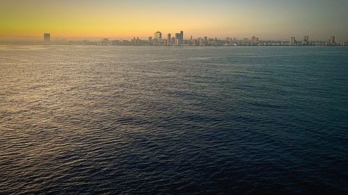 Scenic view of sea and buildings against sky at sunset
