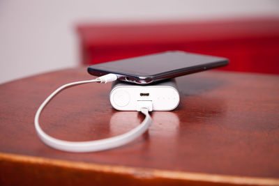 Close-up of mobile phone connected to portable charger on table