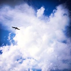 Low angle view of airplane flying against cloudy sky